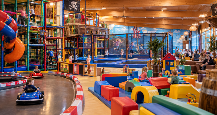 Kinder toben und klettern auf dem überdachten Spielplatz Pirateninsel in Putbus auf Rügen bei Regenwetter.