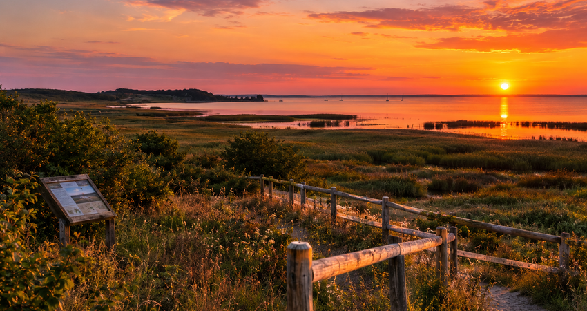 Sonnenuntergang über den sanften Hügeln, Salzwiesen und Boddengewässern im Biosphärenreservat Mönchgut auf Rügen.